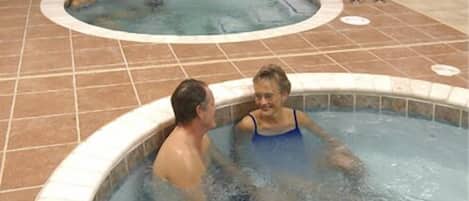 A swimming pool area with two hot tubs and a tiled deck.