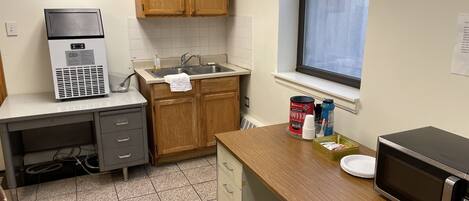 A kitchen with wooden cabinets, a stainless steel sink, a microwave, and a coffee maker.