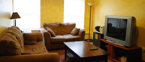 Ein Wohnzimmer mit einer Couch, einem Couchtisch und einem Fernseher auf einem Lowboard.