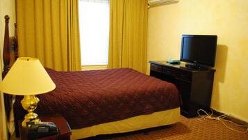 Une chambre d’hôtel comprenant un lit, un bureau avec une télévision, une lampe et un téléphone.