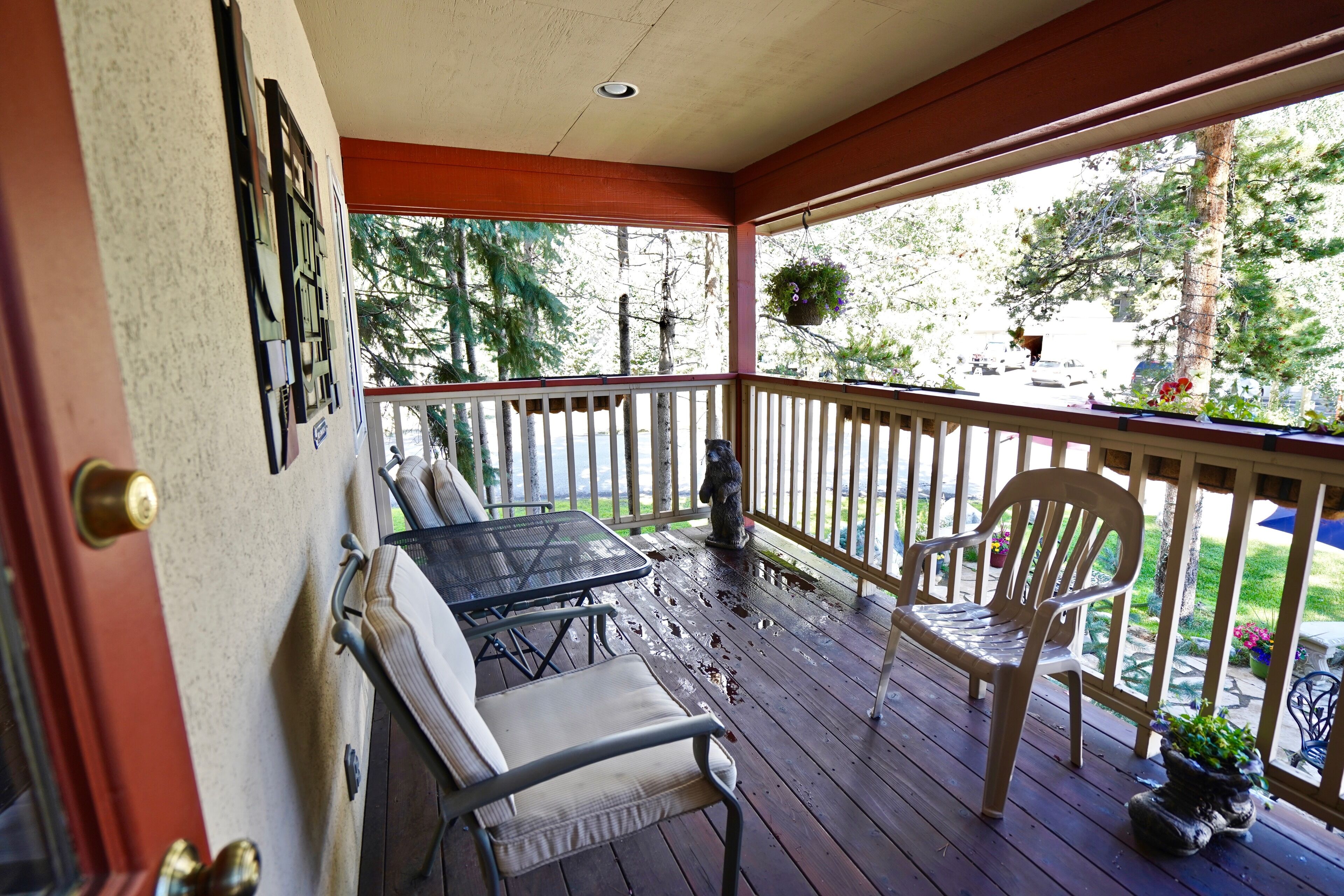 A covered porch with a table and chairs, a hanging planter, and a view of the outdoors.