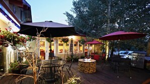 An outdoor patio area with wooden flooring, stone seating, and red umbrellas. - Frisco Inn on Galena Street (Frisco)