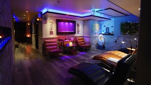 A modern lounge area with leather seating, a flat-screen TV, and ambient lighting. - Frisco Inn on Galena Street (Frisco)
