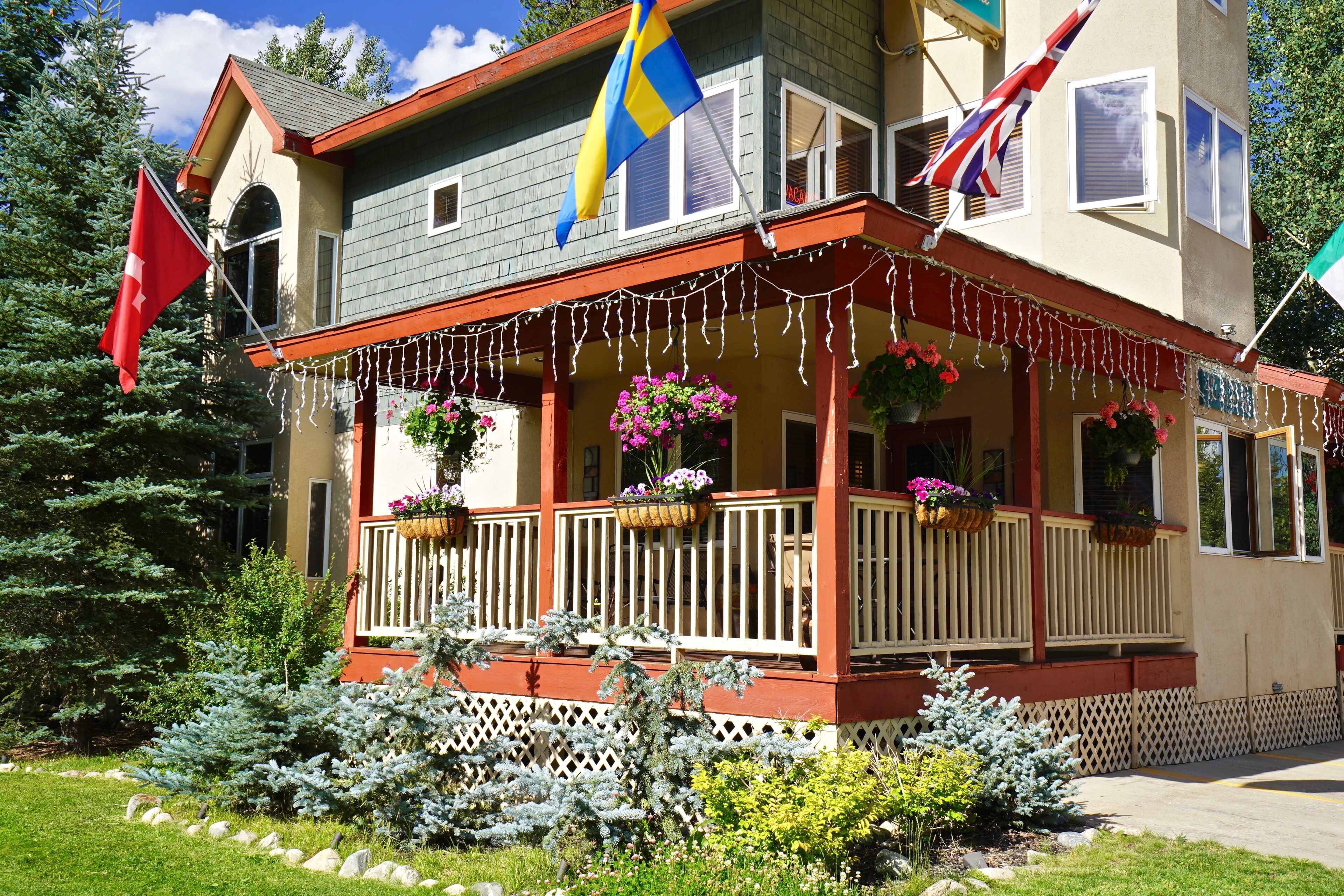A two-story building with a porch decorated with string lights and flower baskets.