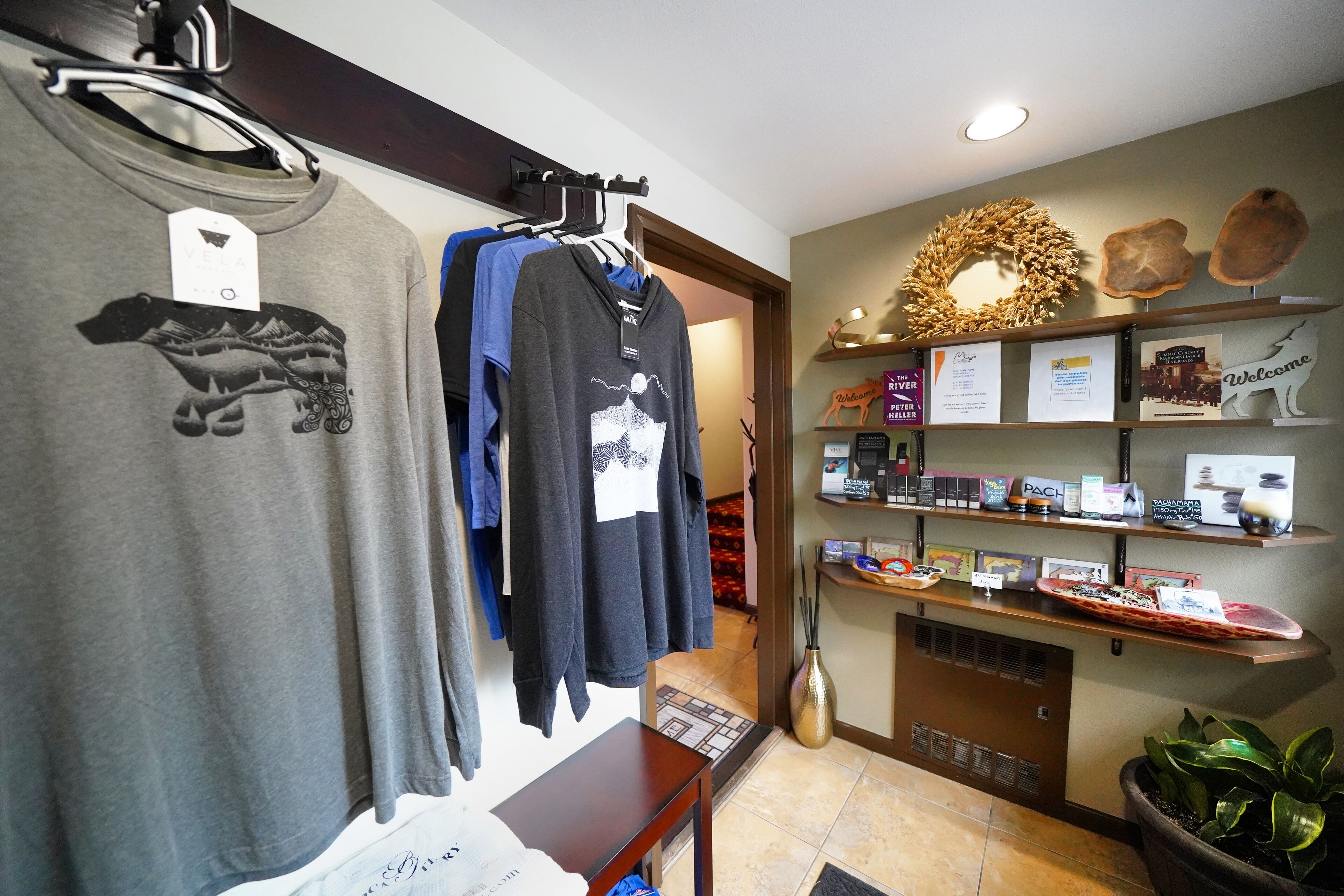 Un hall d’hôtel comprenant un comptoir d’accueil, un présentoir mural où sont exposés des objets d’artisanat local, et un espace détente avec une table et des chaises.