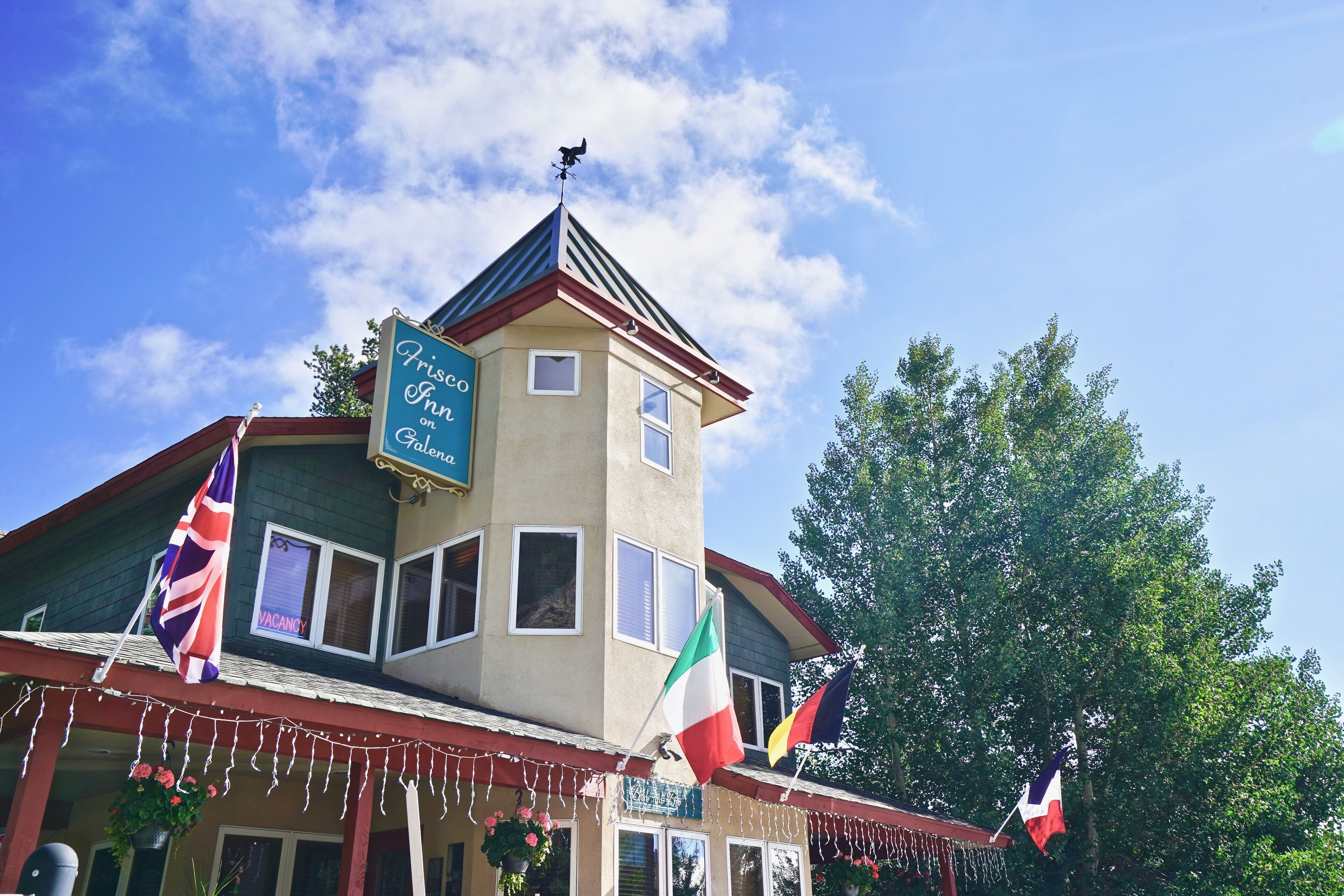 A building with a sign reading "Frisco Inn" and multiple flags.