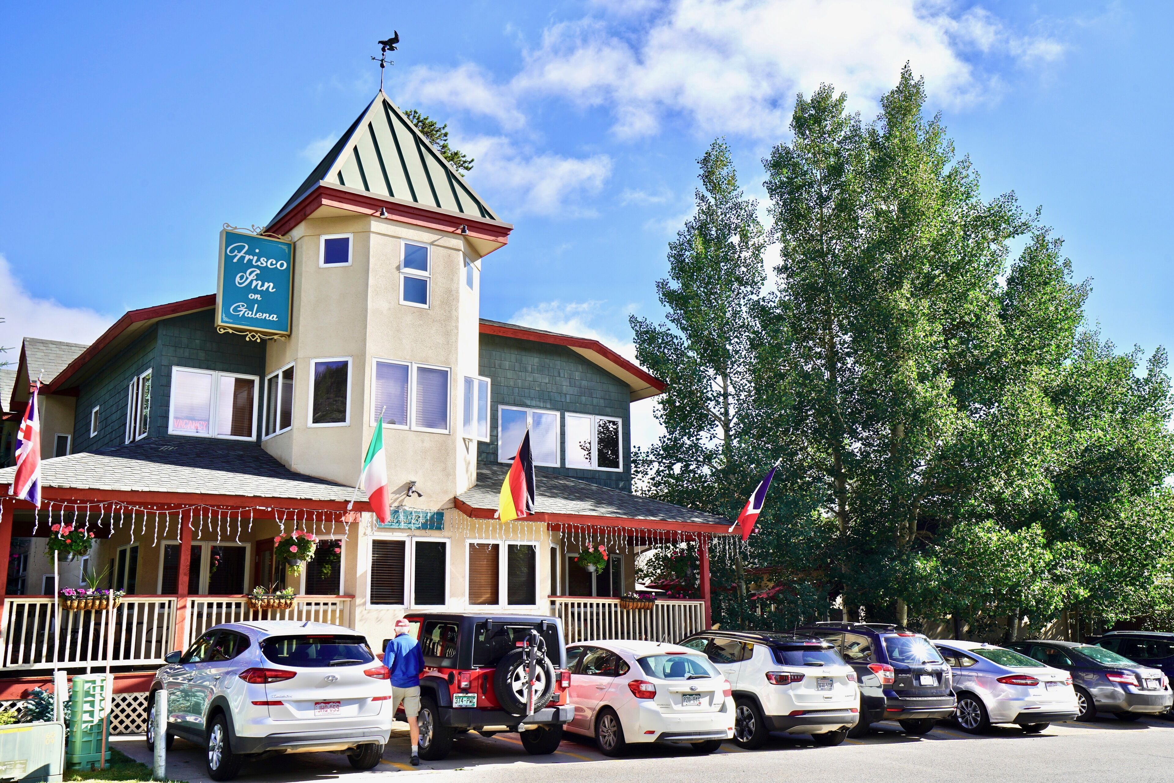 A building with a tower, a sign reading "Frisco Inn," and multiple flags.