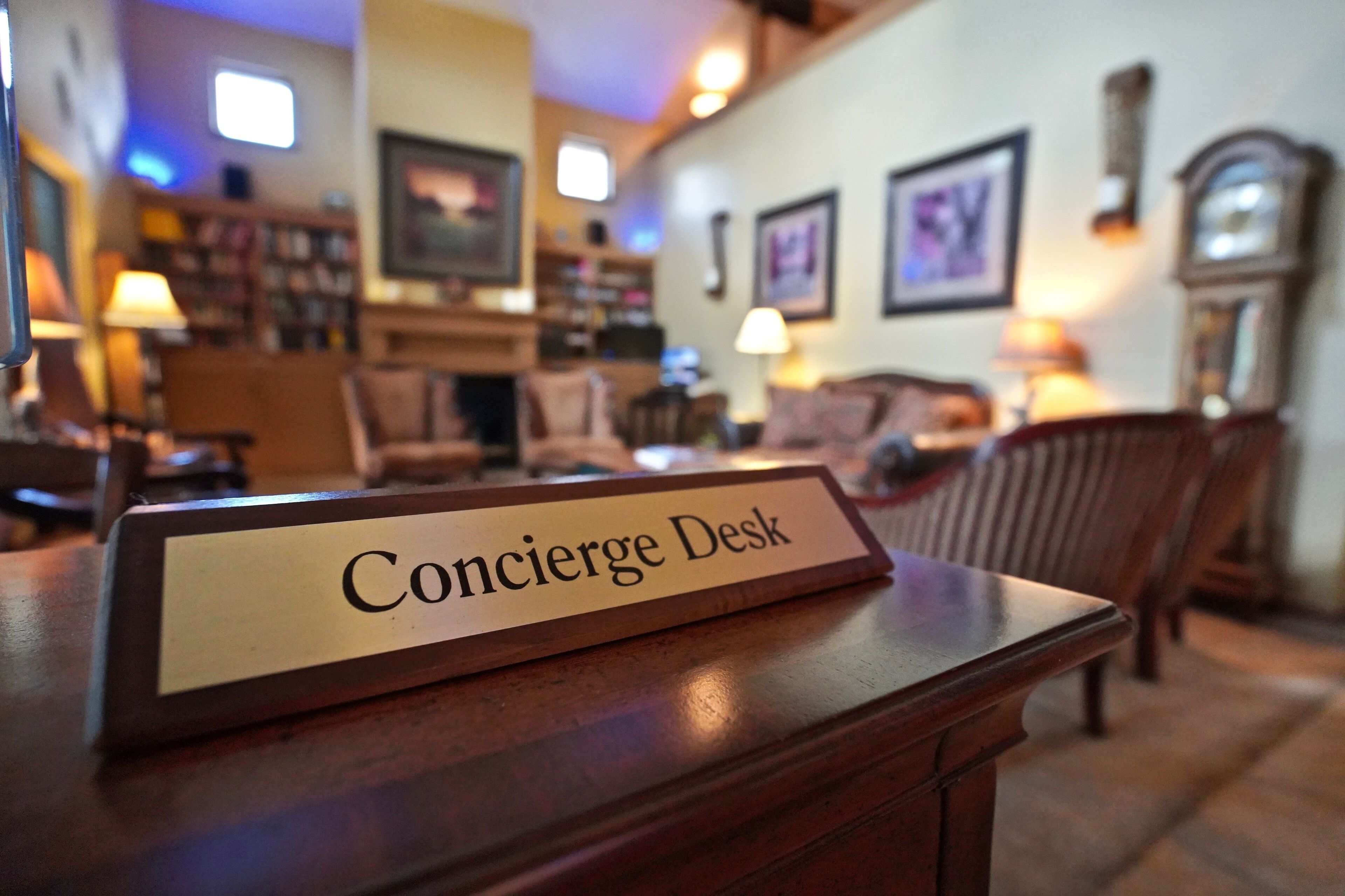 A Concierge Desk in a warmly lit room with wooden furniture and framed pictures on the walls.