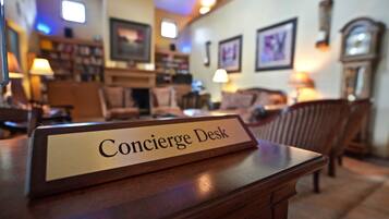 A Concierge Desk in a warmly lit room with wooden furniture and framed pictures on the walls.