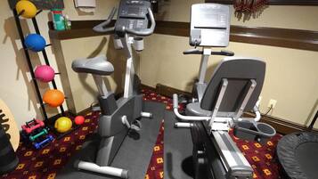 A gym with two treadmills, a wall-mounted TV, and a poster on the wall.