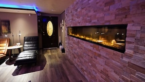 A modern interior with a stone wall, a fireplace, leather seating, and a round table. - Frisco Inn on Galena Street (Frisco)