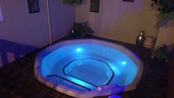 Een hottub met blauw licht, houten vloer en wanddecoraties.