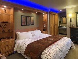 A bedroom with a large bed, wooden wardrobe, and built-in shelves.