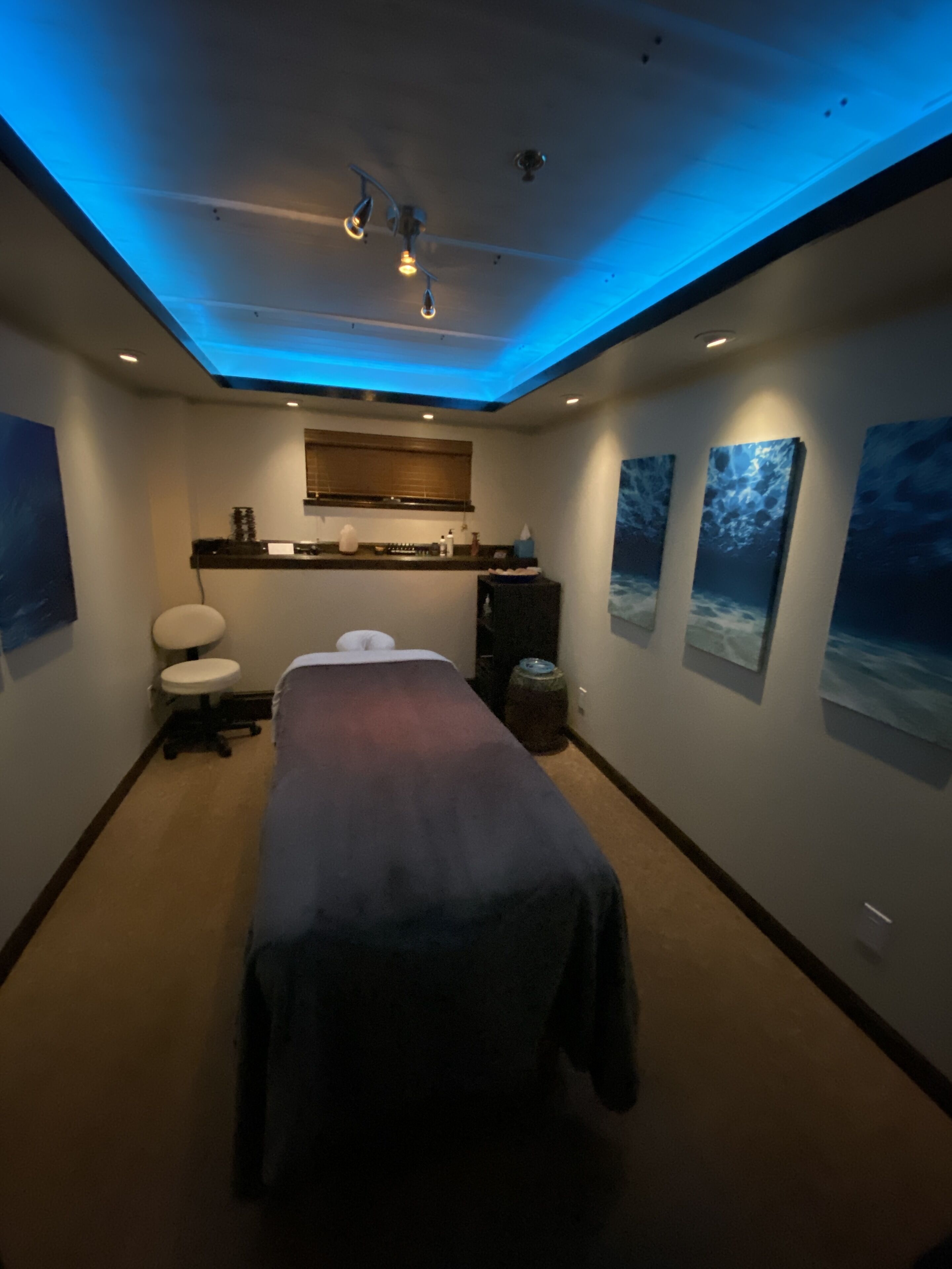 A room with a massage table, a small window, a sink, and a cabinet.