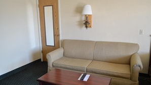 A room with a beige sofa, a wooden table, a wall-mounted lamp, and a door. - National 9 Inn Wellington (Wellington)