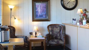 A hotel room with a wooden-framed desk, two chairs, a clock, and a framed picture on the wall. - National 9 Inn Wellington (Wellington)