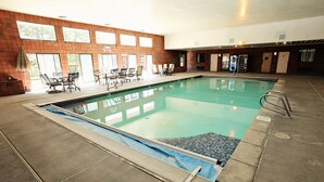 An indoor swimming pool with tiled walls, a blue pool deck, and a seating area with tables and chairs. - National 9 Inn Wellington (Wellington)