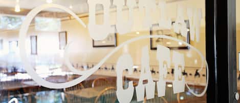 Interior de un restaurante con un separador de vidrio que muestra la frase 'Country Cafe' en una tipografía estilizada.