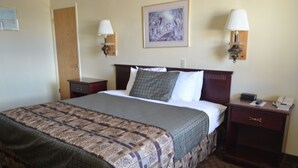 A hotel room with a large bed, two bedside tables, a nightstand, a lamp, and a painting on the wall. - National 9 Inn Wellington (Wellington)
