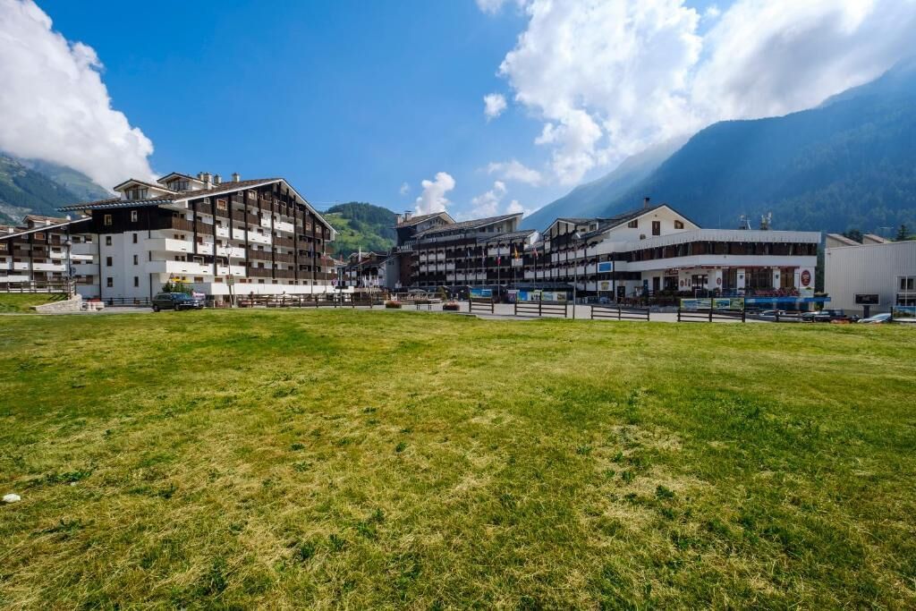 A hotel with multiple floors, a central courtyard, and mountainous background.