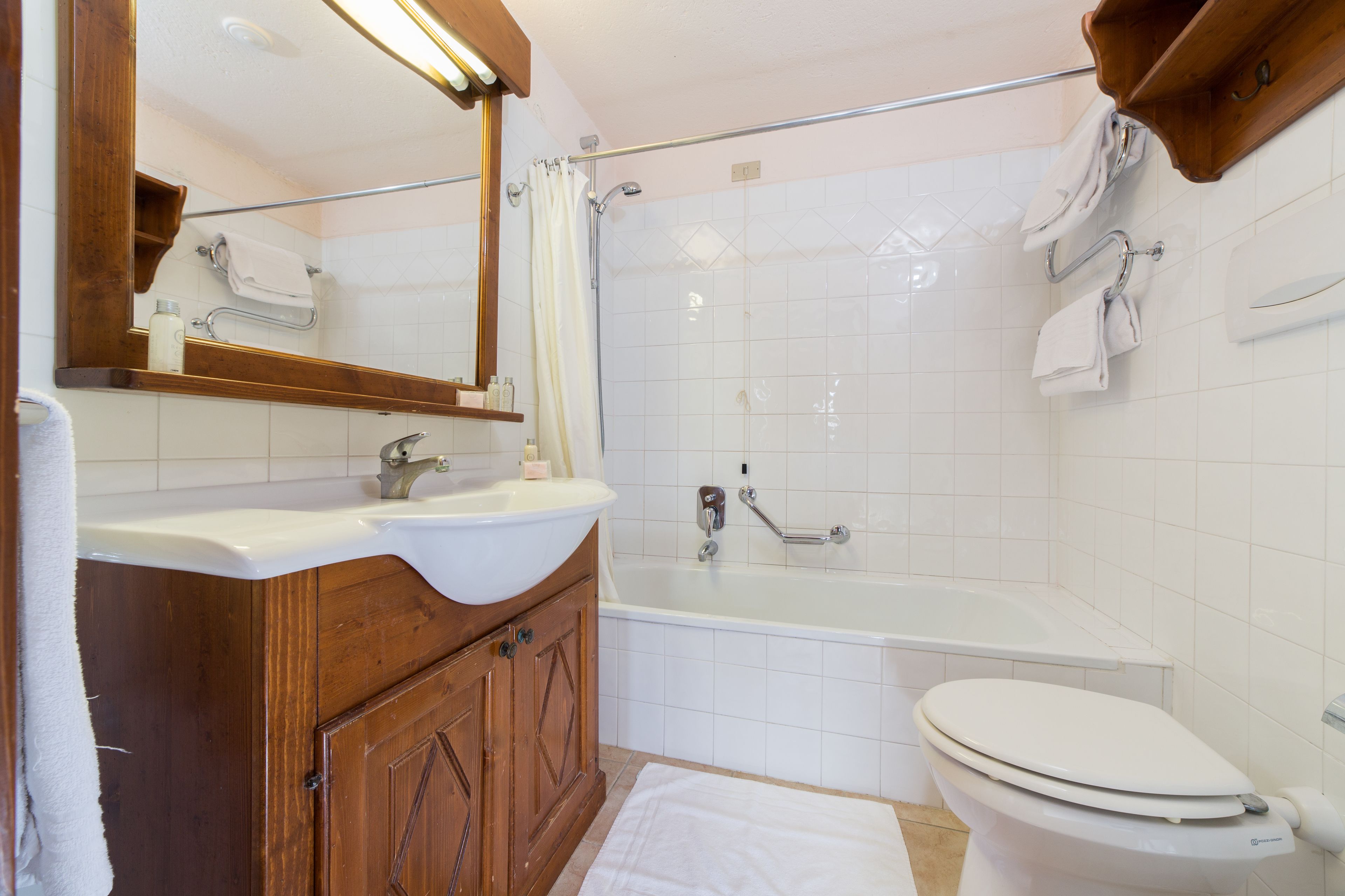 Une salle de bain avec un meuble-lavabo en bois, un lavabo blanc, une baignoire et des toilettes.