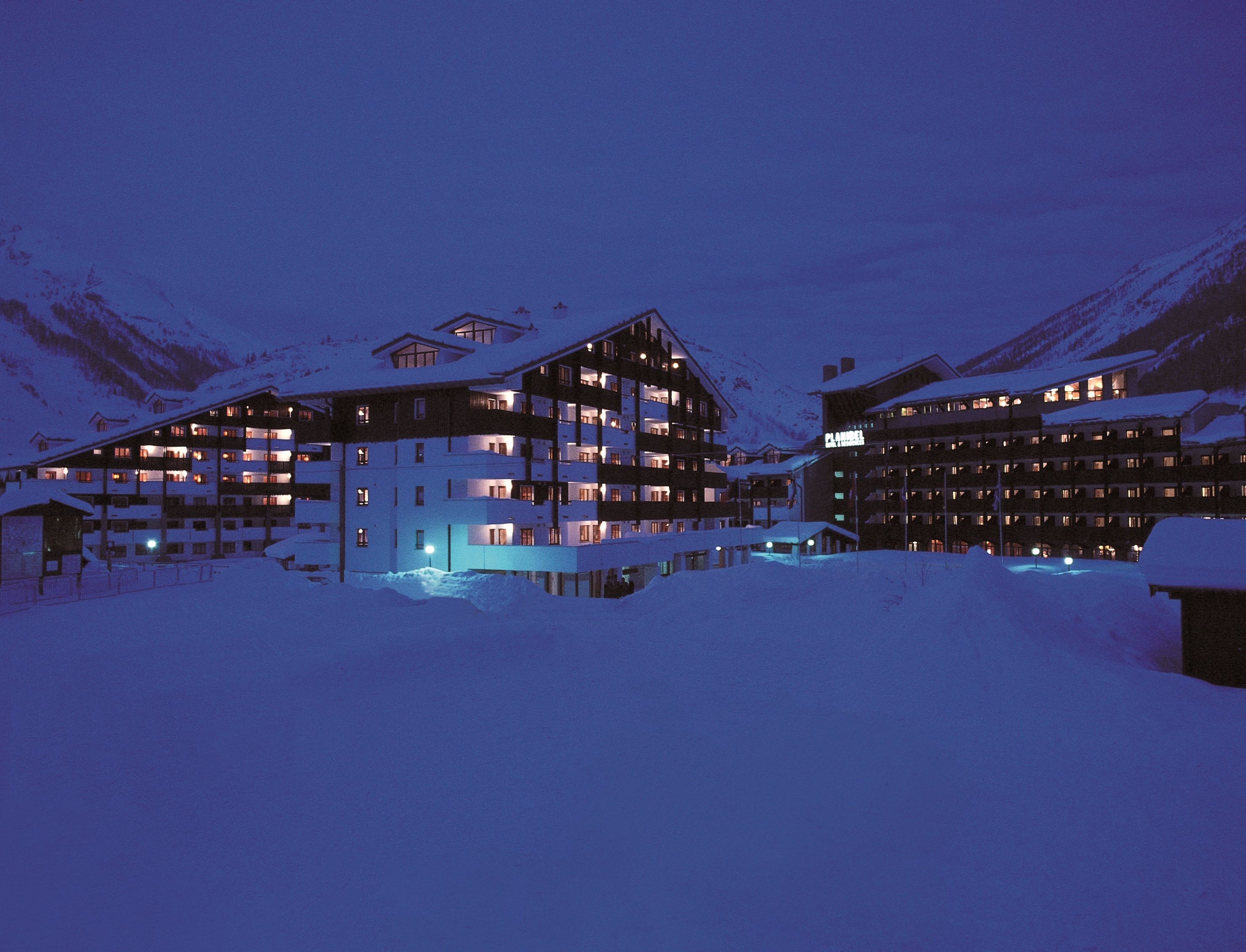 Ein mehrstöckiges Hotel mit Balkonen und verschneiter Umgebung.