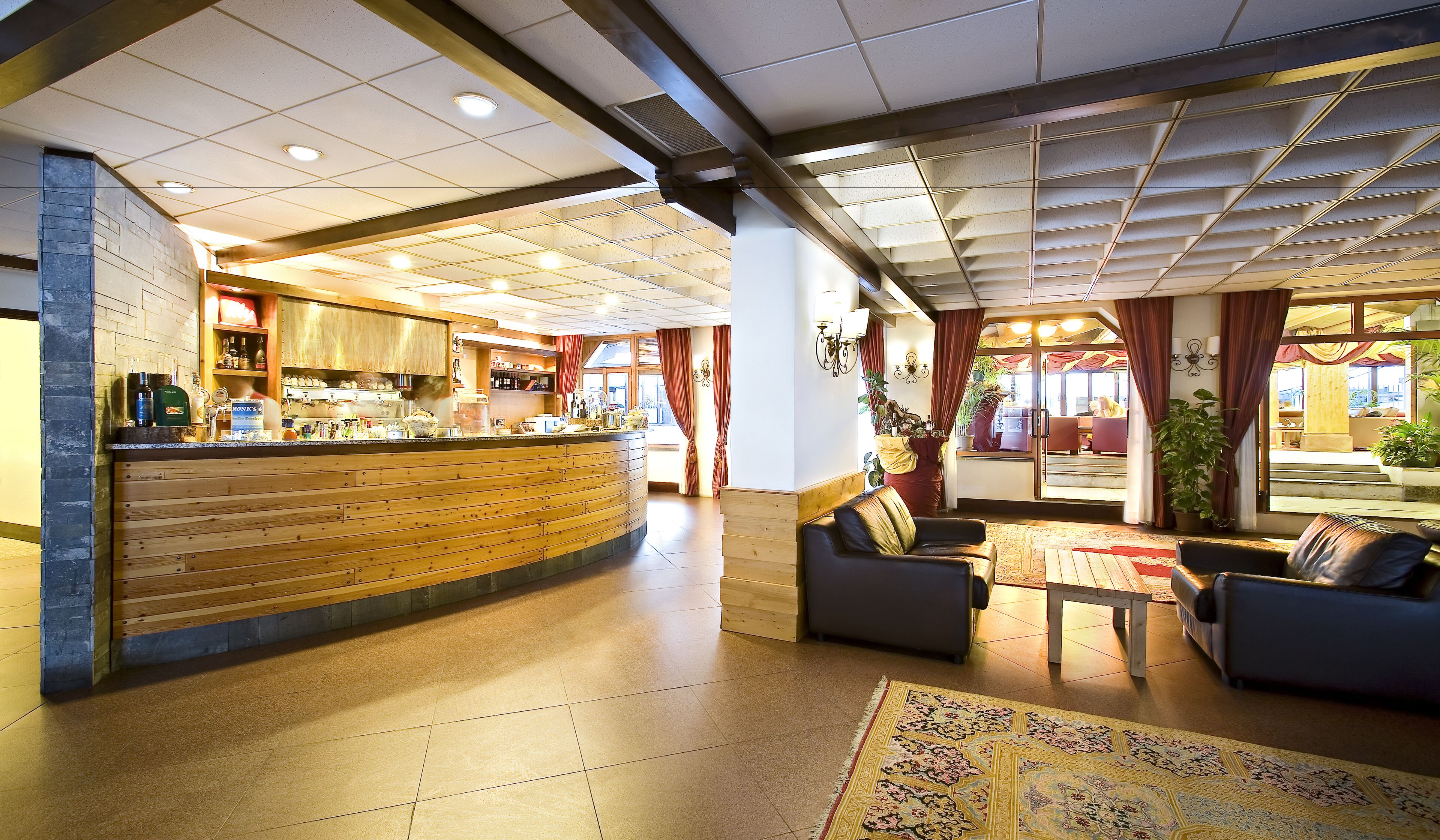 A hotel lobby with a reception desk, seating area, and a view of the outdoor terrace.