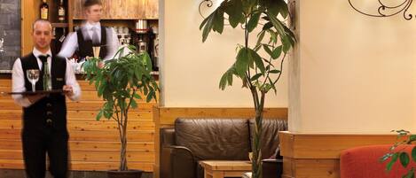 A hotel lobby with wooden furniture, a bar area, and a reception desk.
