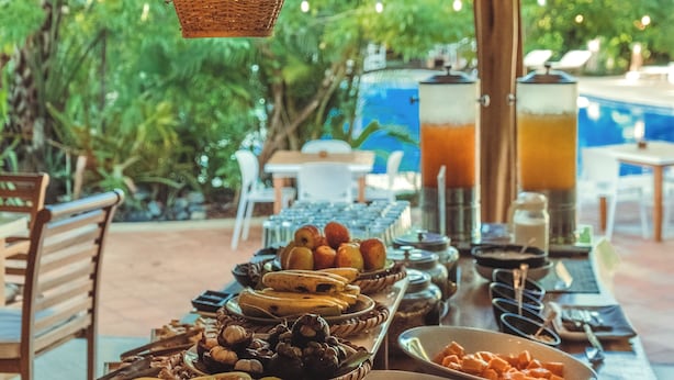 A buffet table with various food items and a pool in the background.