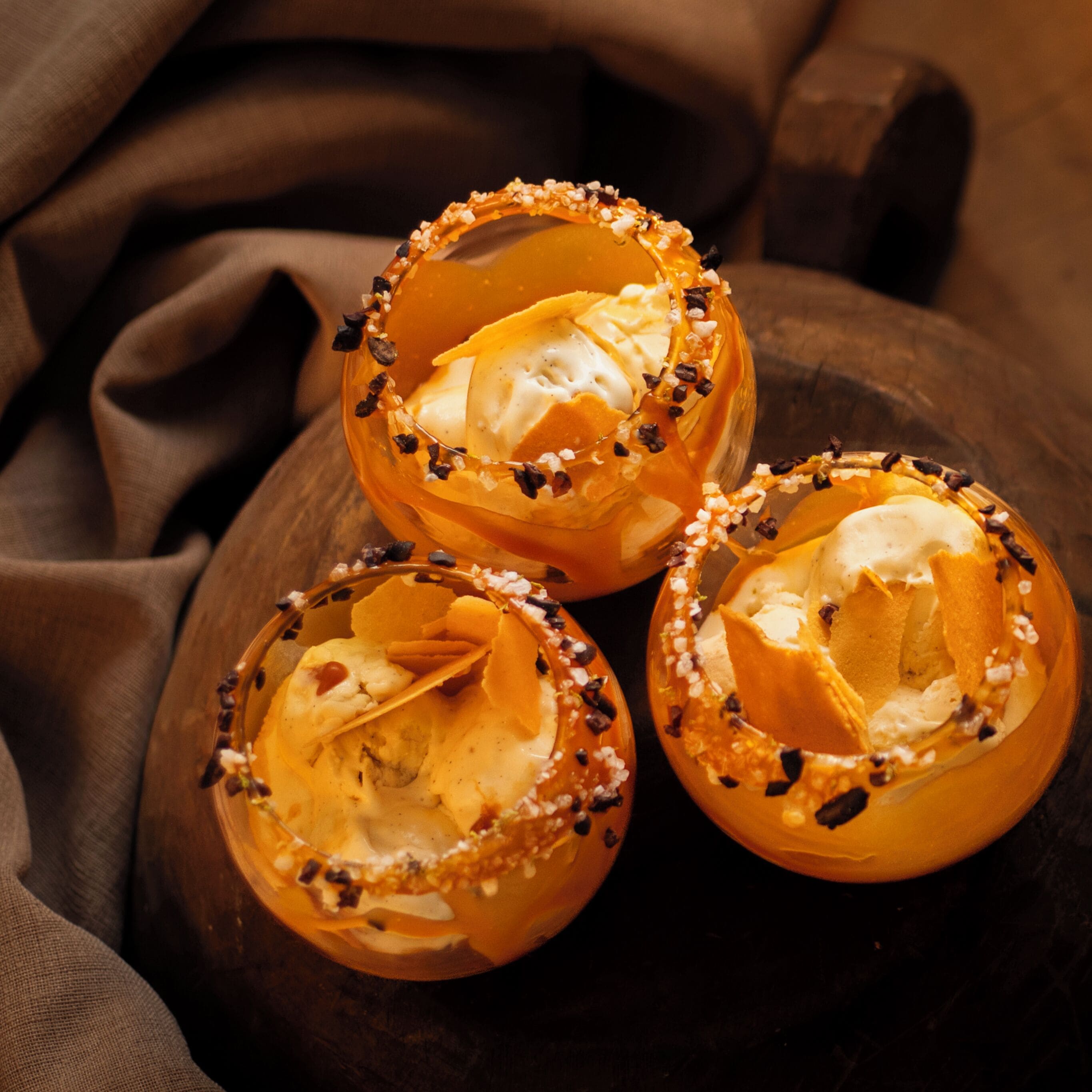 Trois verres de dessert disposés sur une planche en bois.