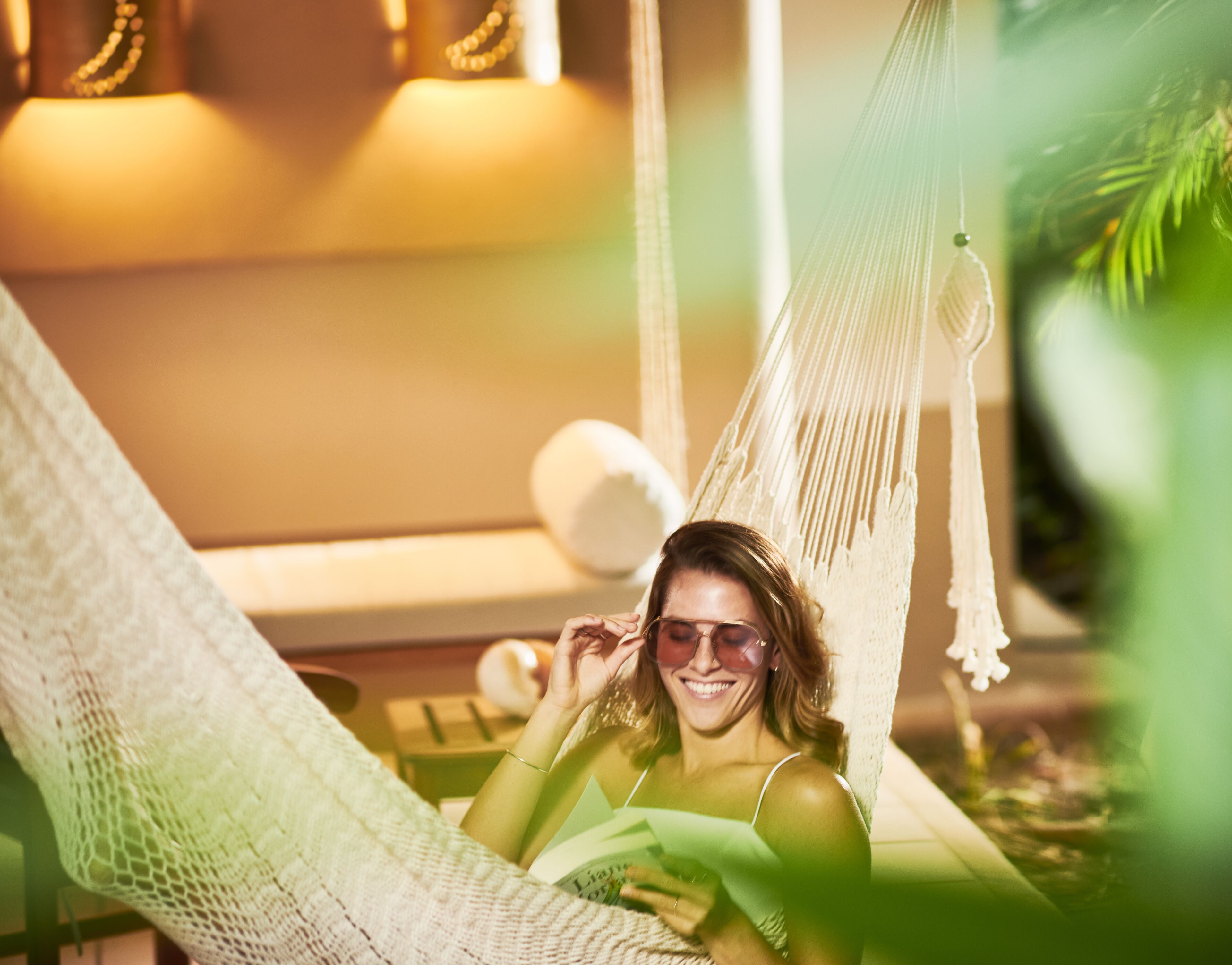 A person relaxing in a hammock with a book, indoors.