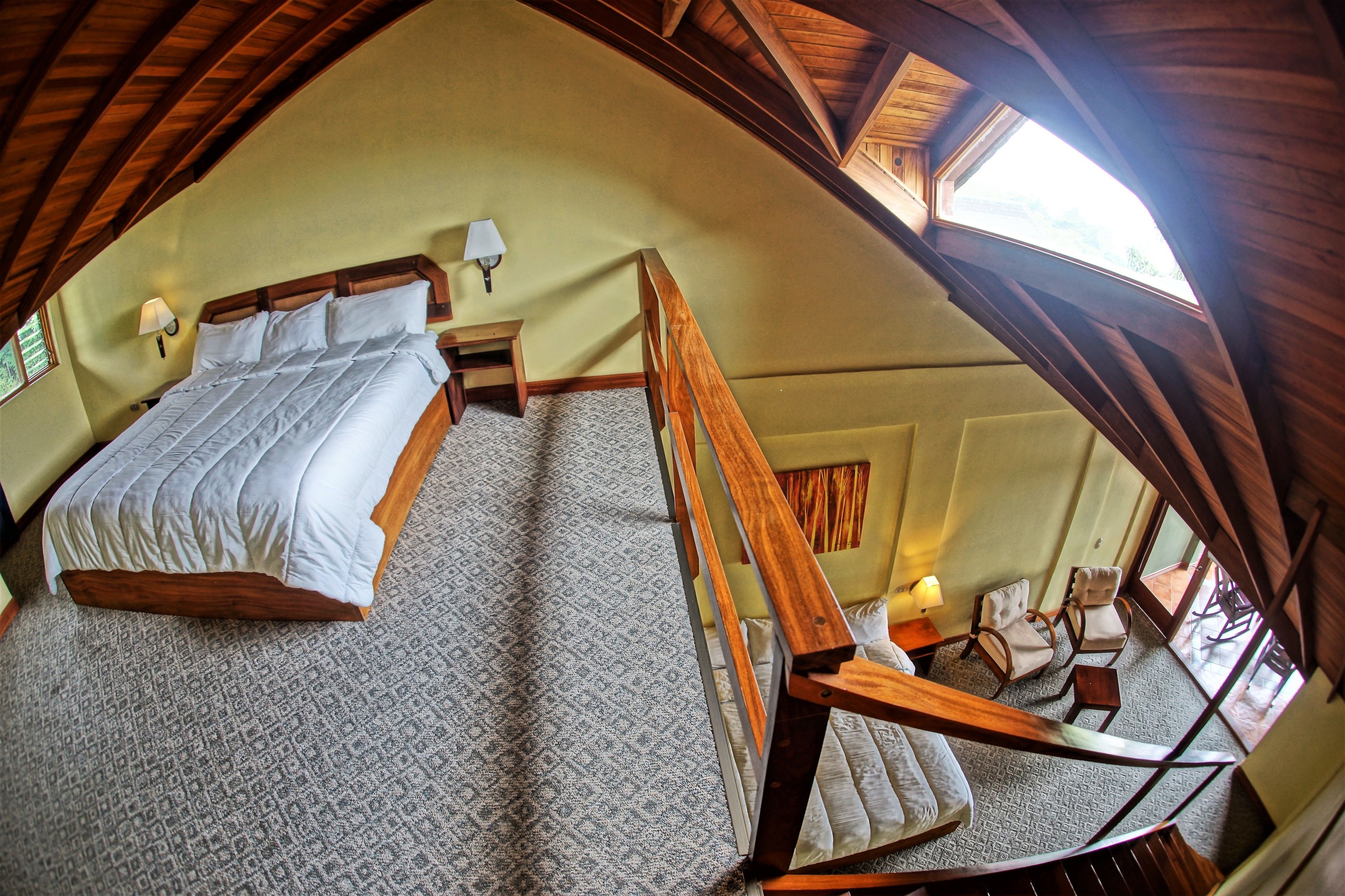 A bedroom with a large bed, a wooden chair, and a small table.