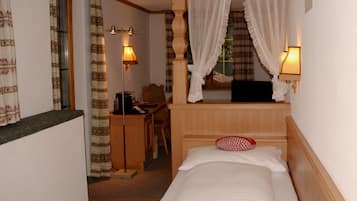 A bedroom with a bed, a desk, a chair, and a window with curtains.