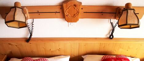 A wooden headboard with two wall-mounted lamps and two heart-shaped pillows with reindeer designs.