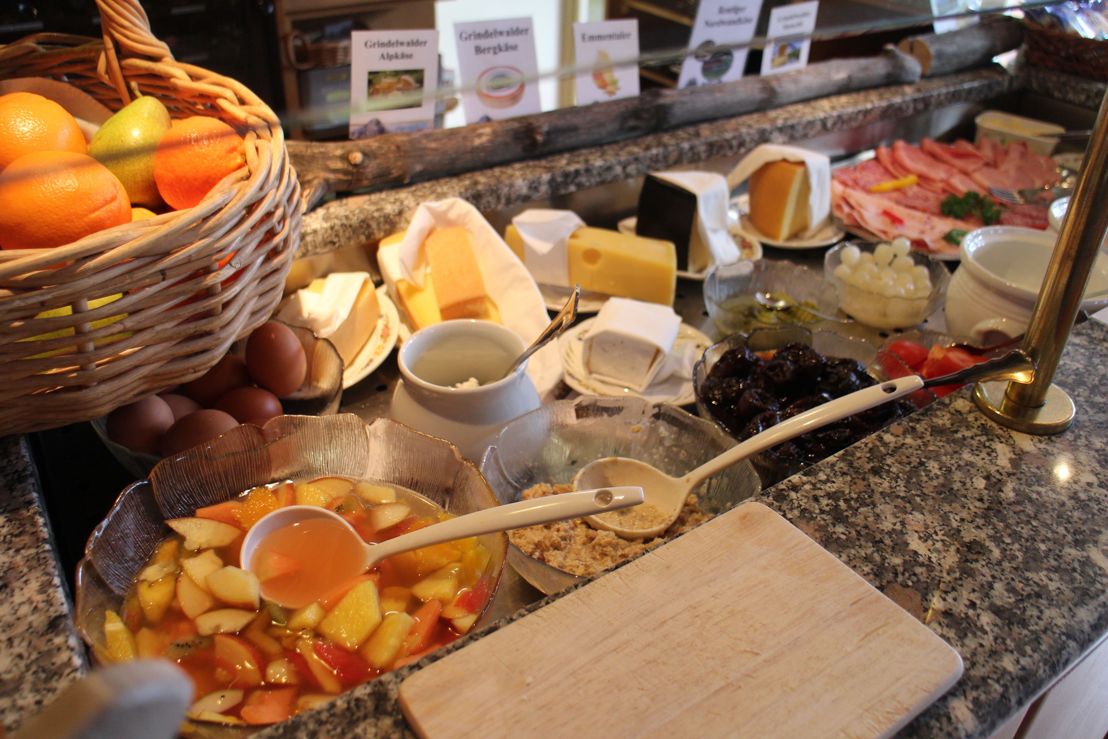 A buffet with various food items including fruits, cheeses, and meats.