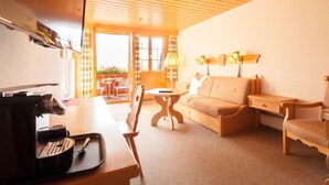 Una habitación acogedora con techo de madera, un sofá, una mesa con lámpara y una cafetera.