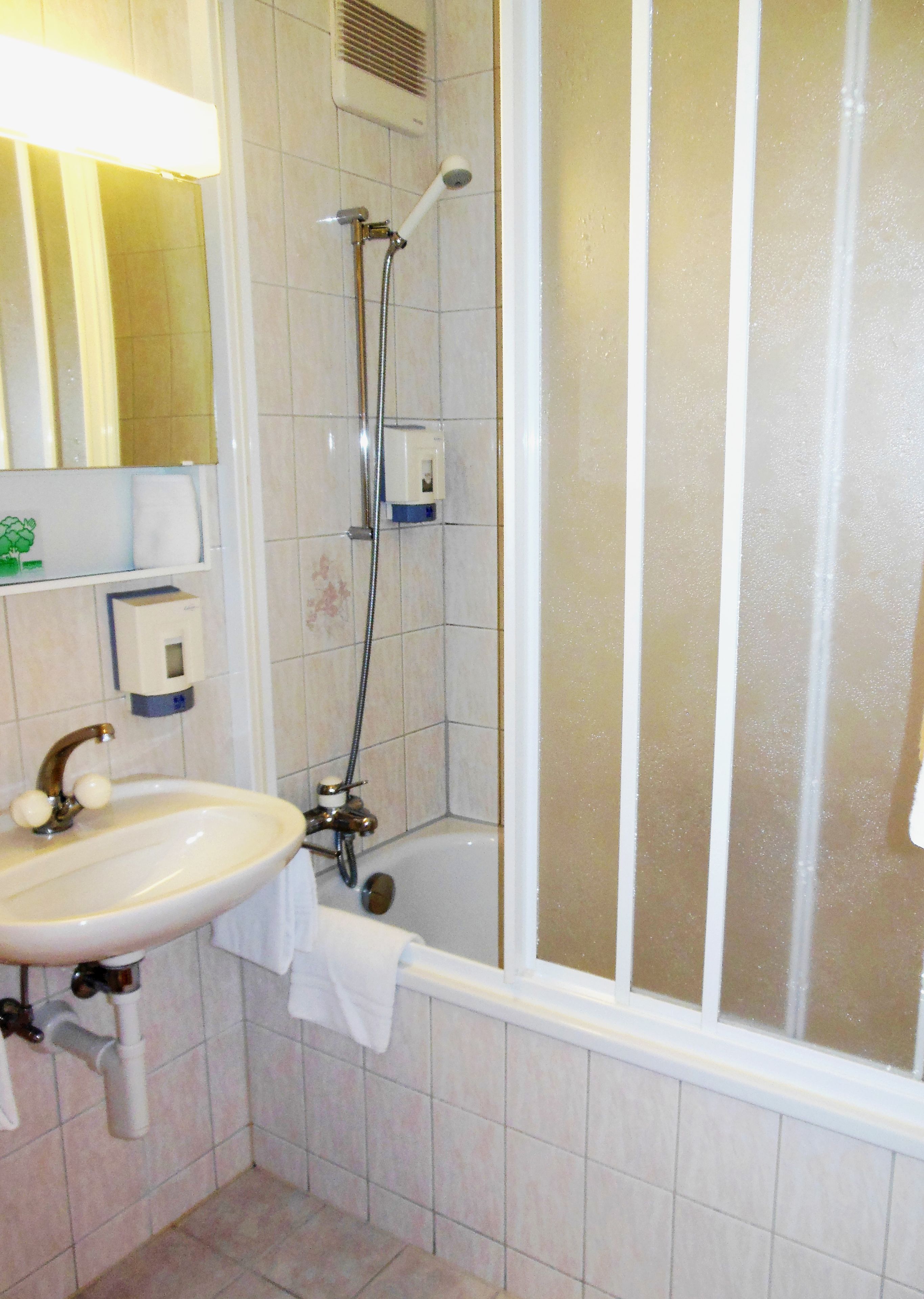 Un baño con lavamanos, ducha y espejo.