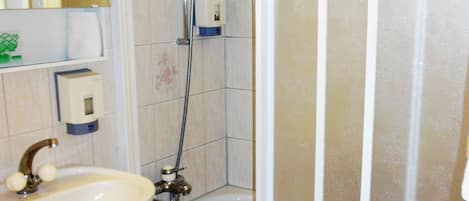 Un baño con lavamanos, ducha y espejo.