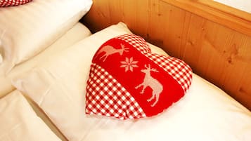 A bed with a checkered pillow and a heart-shaped pillow with animal designs.