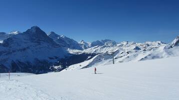 A snowy mountain landscape with a ski lift and a person skiing.
