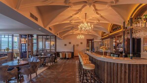 A bar area with a wooden bar counter, bar stools, and a chandelier. - Glenroyal Hotel & Leisure Club (Maynooth)