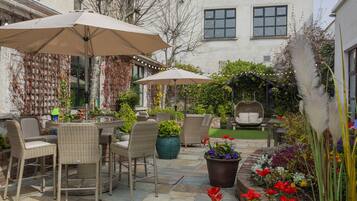 An outdoor patio area with wicker furniture, potted plants, and string lights.