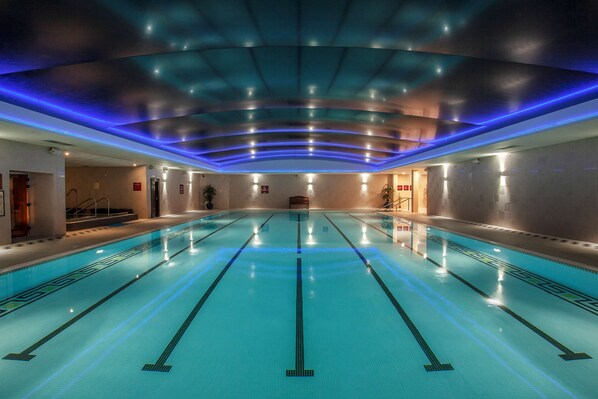 A large indoor swimming pool with clear lane markings and overhead lighting.
