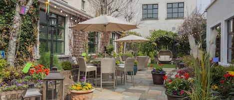 An outdoor patio with wicker furniture, potted plants, and string lights.