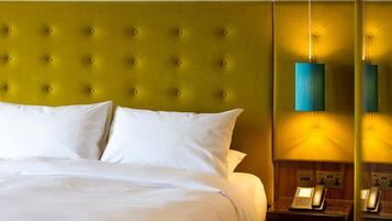 A hotel room with a tufted headboard, white bedding, and a bedside telephone.