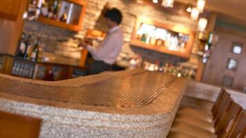 A bar area with a stone countertop and wooden seating.