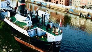 Un barco grande atracado en un puerto con edificios históricos al fondo.