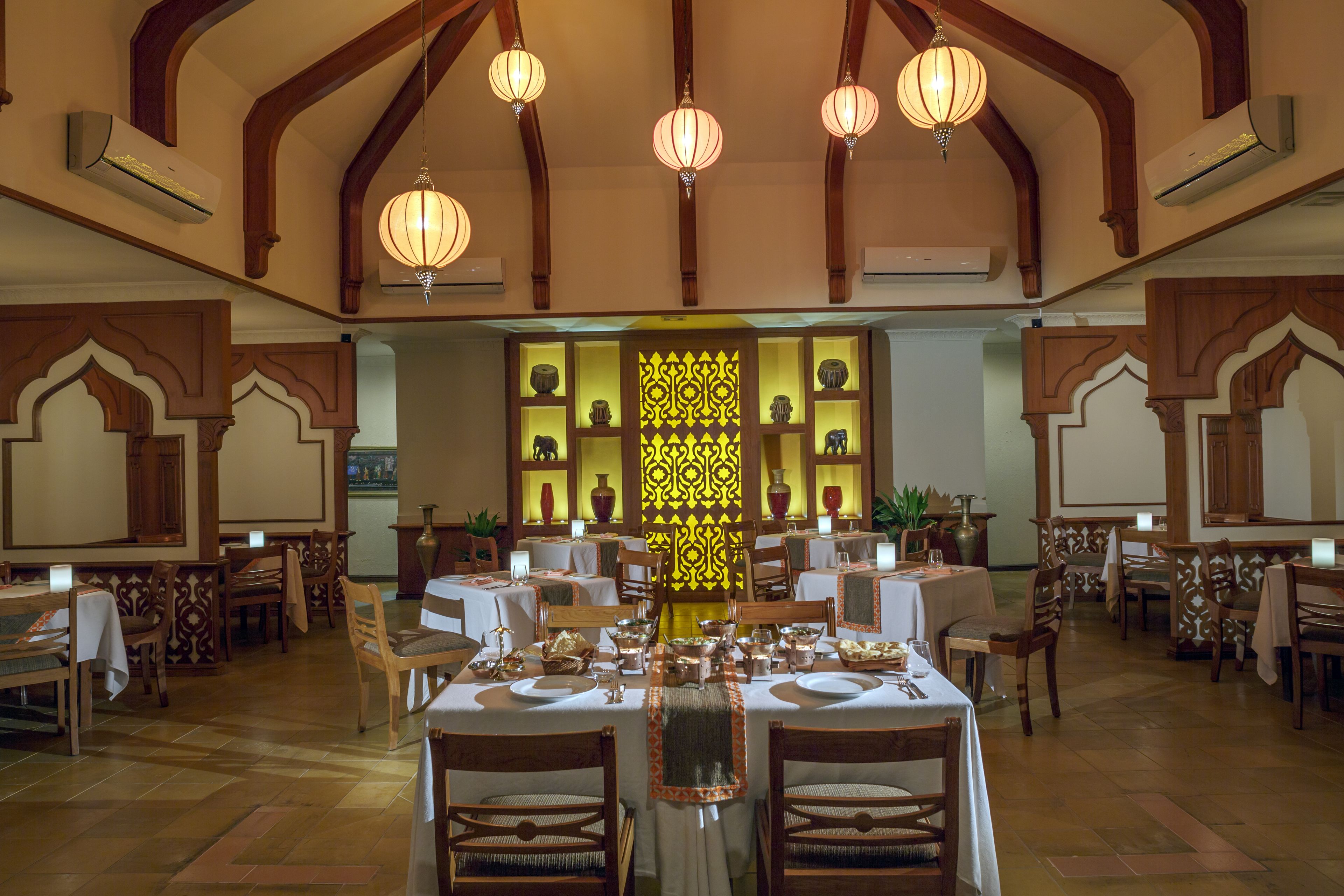 A dining area with tables set for a meal, wooden chairs, and decorative elements.