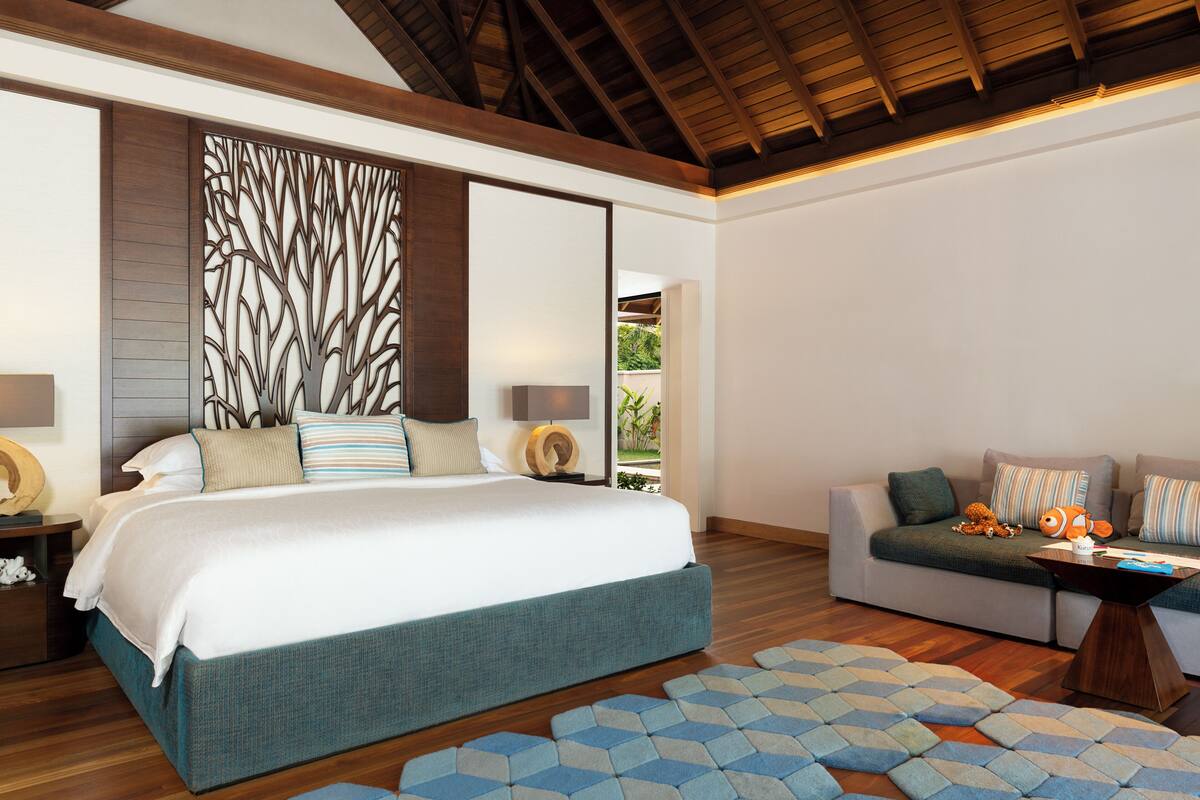 A bedroom with a large bed, a sofa, and a decorative wall panel.