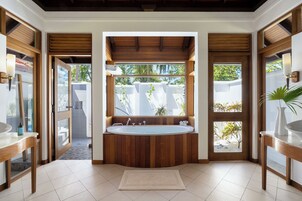 Un baño con una bañera independiente, paneles de madera, un ventanal y vistas al exterior.
